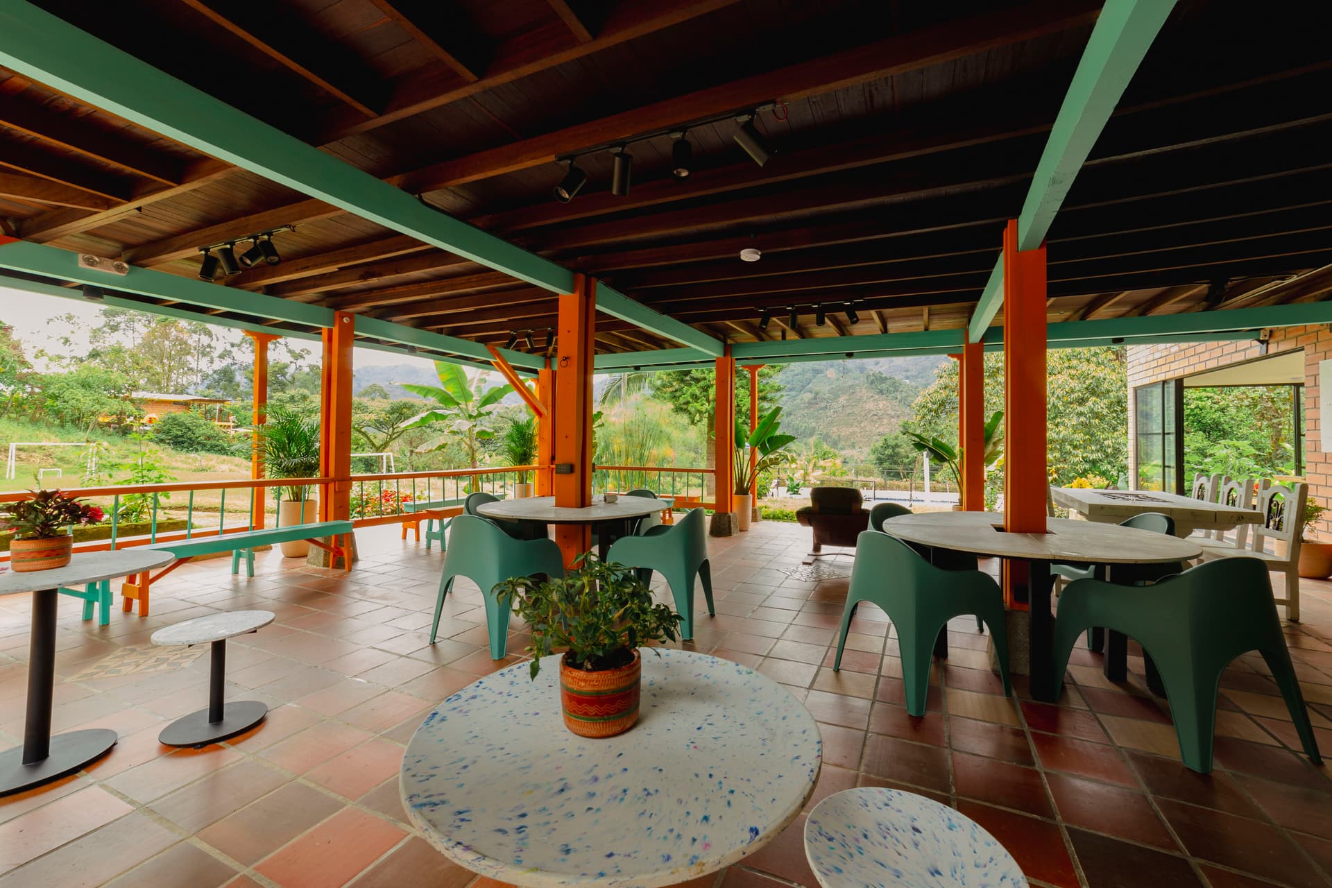 Two white oval tables around orange columns with turquoise chairs in the shared space